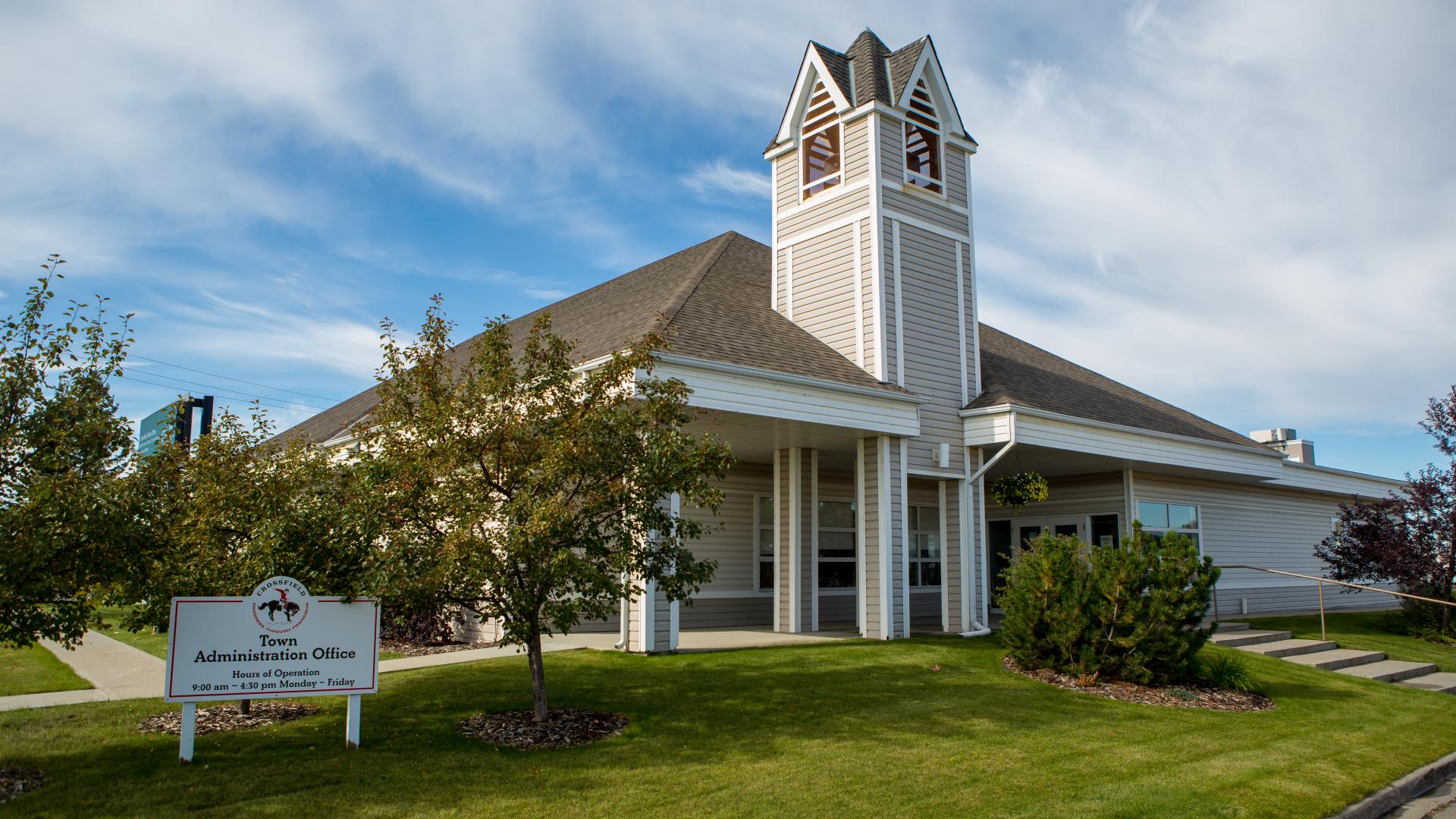 A building sitting on a green lawn with trees and shrubs