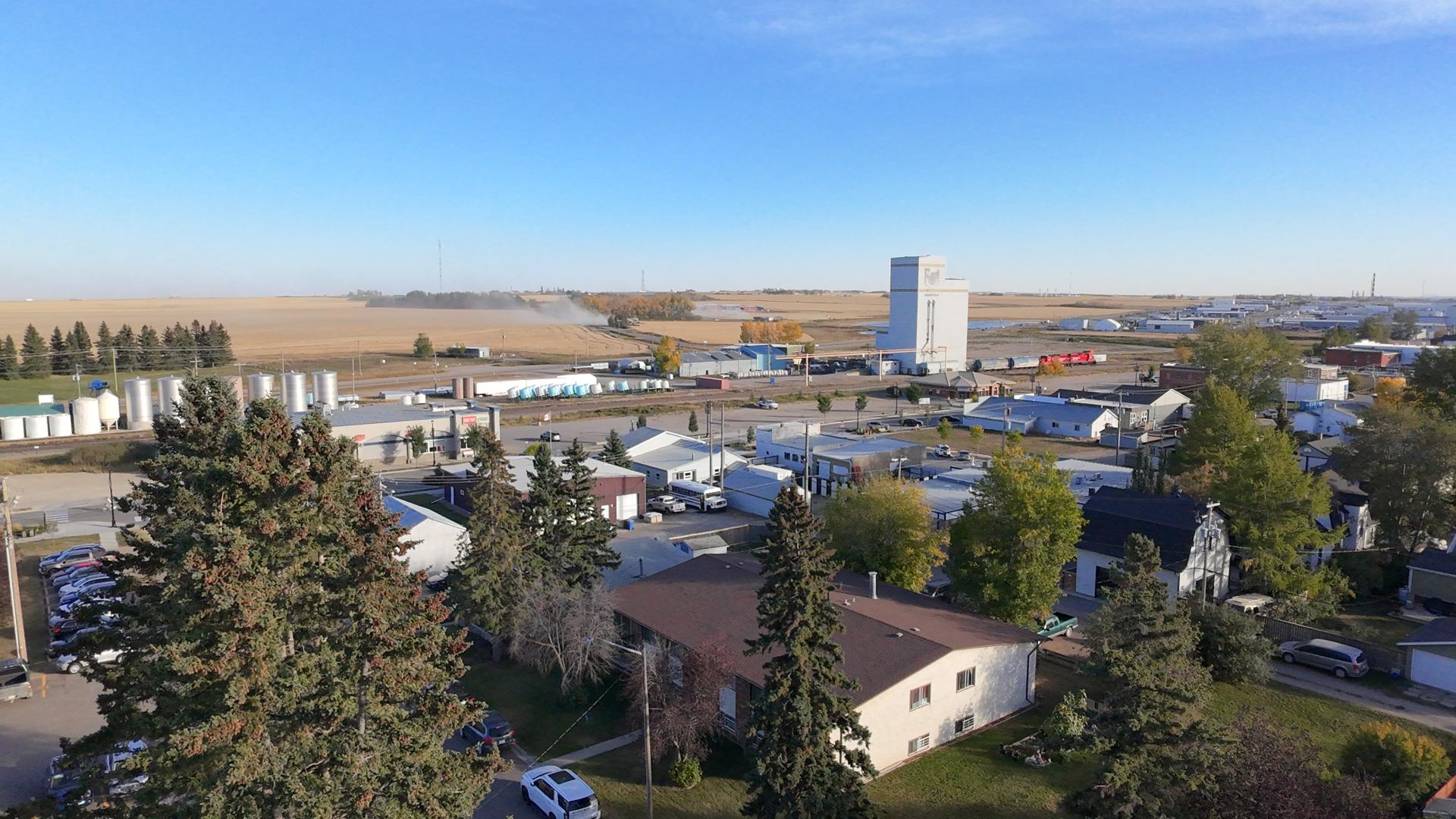 Ariel view of Town with a combine working a field in the distance kicking up dust