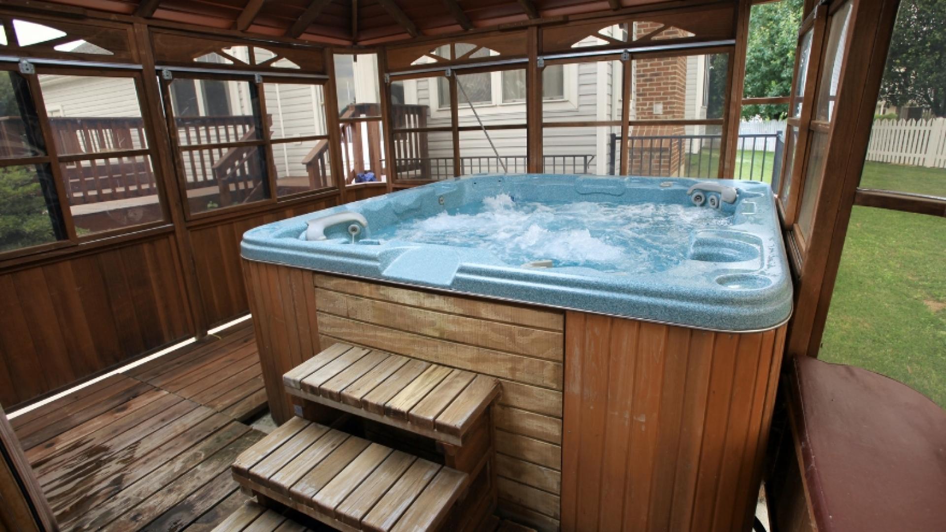 Two steps up to a covered hot tub in a residential backyard 