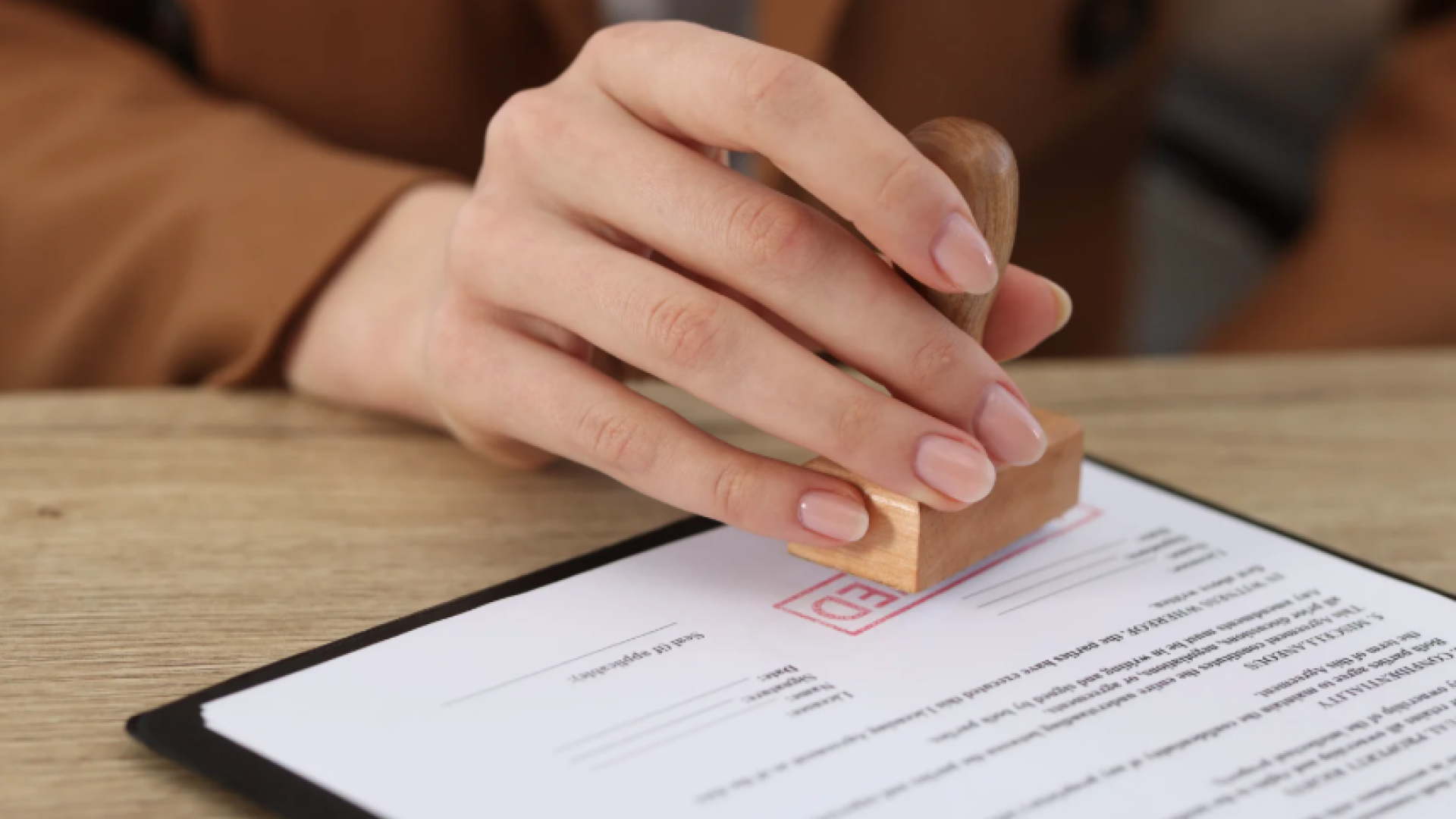 A person presses a stamp onto a document, indicating official approval or business licensing.