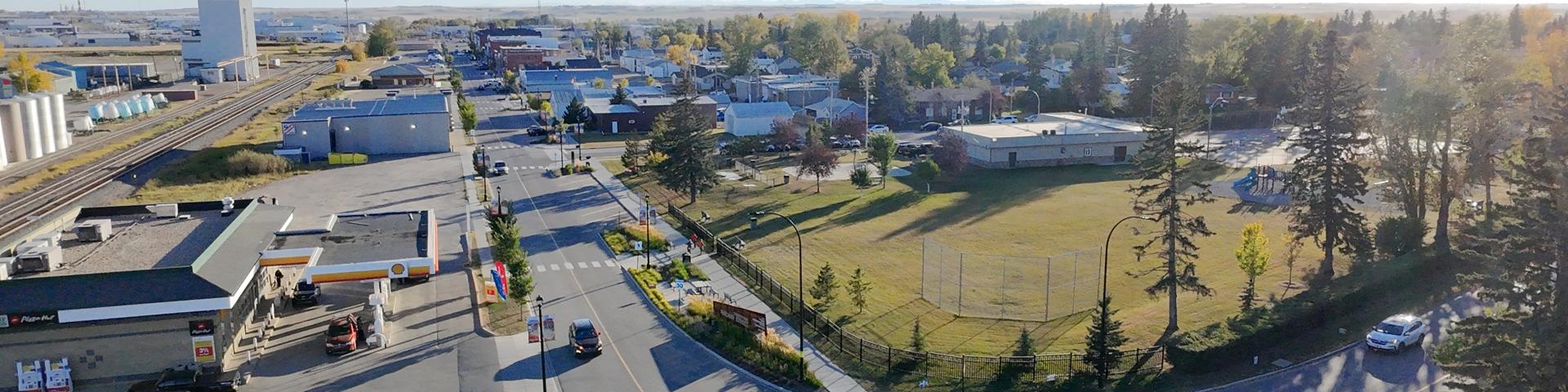Ariel view of Town on a sunny day, with cars driving on the street, overlooking a park and a gas station